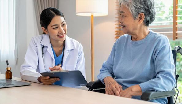 シニア女性に聞き取りをする若い介護士 シニア女性に聞き取りをする若い介護士の写真