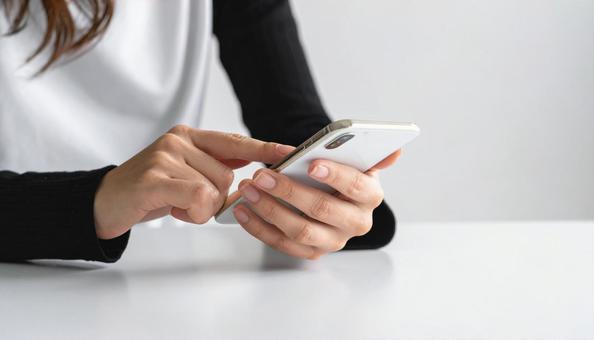 携帯を操作する女性の手元とノートパソコン 携帯を操作する女性の手元とノートパソコンの写真
