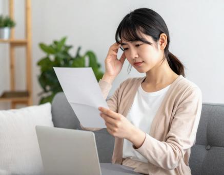 請求書を見て悩んでいる女性の写真
