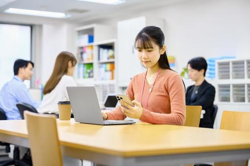 仕事中にスマホを確認する女性社員 ビジネスウーマン,スマホ,パソコンの写真素材