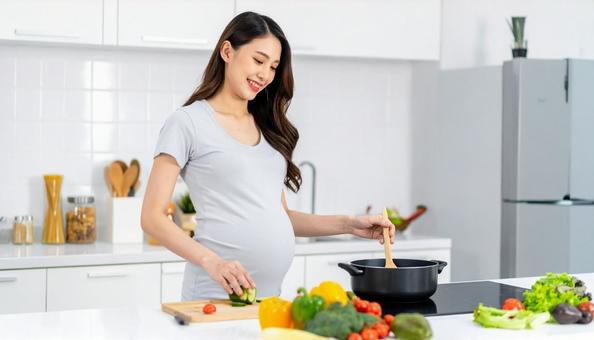 キッチンで料理をする妊婦 キッチンで料理をする妊婦の写真
