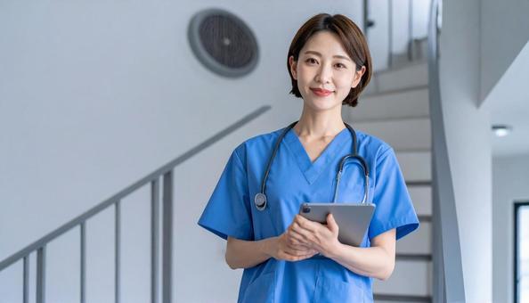 病院の階段下に立つ女性の医療従事者の写真