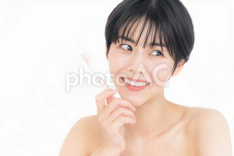 歯磨きをする白バックの若い女性 ホワイトニング,女性,オーラルケアの写真素材