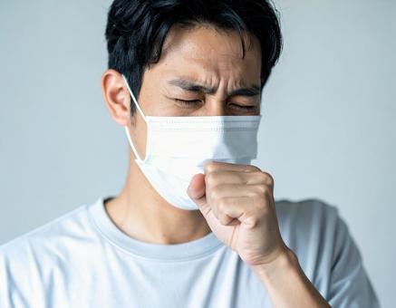 マスクを着用して咳をするの男性 マスクを着用して咳をするの男性の写真