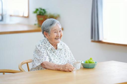 窓の近くに座り笑うショートヘアの高齢女性 女性,シャインマスカット,ぶどうの写真素材