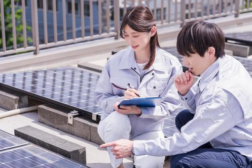 ソーラーパネルをチェックする作業員。 ソーラーパネルをチェックする作業員。 女性,男性,人物の写真素材