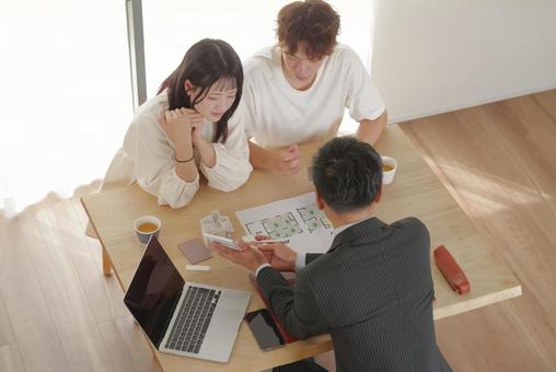 営業マンと家づくりの相談をする若い夫婦 営業マンと家づくりの相談をする若い夫婦 住宅,家,新築の写真素材