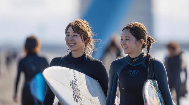 海辺の砂浜でサーフボードを抱え歩く女性の写真