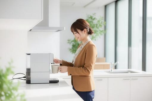 会社のコーヒーメーカーを使用する女性 会社のコーヒーメーカーを使用する女性の写真