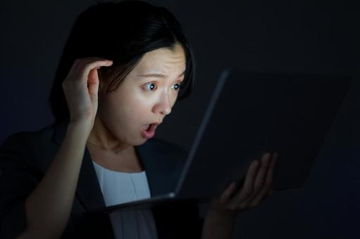 女性がノートPCを見て頭を押さえて驚く 女性,ノートパソコン,持つの写真素材