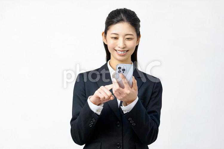 スマホを見る若い女性　スーツ　オフィス スマホ,ビジネスウーマン,スマートフォンの写真素材