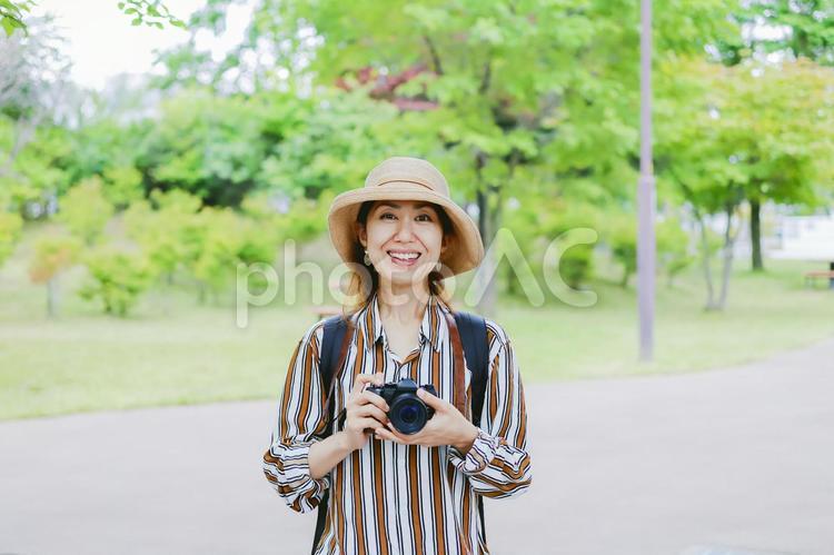 カメラを持って微笑む女性 カメラ,一眼レフ,一眼レフカメラの写真素材