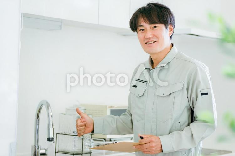 キッチンと作業着姿の男性（水道） 水道屋,水漏れ,漏水の写真素材