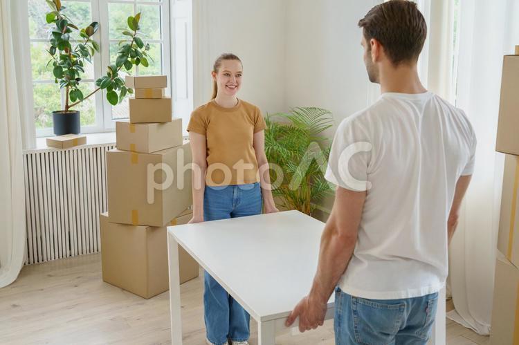 男性と机を運ぶ笑顔の女性 机,運ぶ,笑顔の写真素材