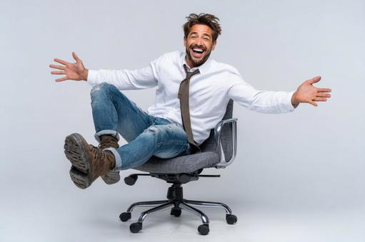 オフィスチェアで楽しげに笑うビジネスマン オフィスチェアで楽しげに笑うビジネスマンの写真