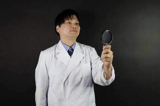 虫眼鏡を見つめる医師 虫眼鏡を見つめる医師の写真