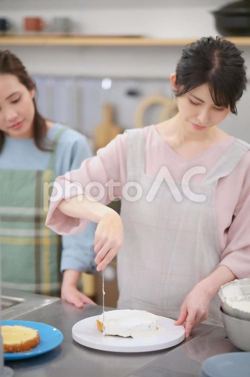 スポンジケーキに生クリームをつける先生と生徒 女性,先生,生徒の写真素材