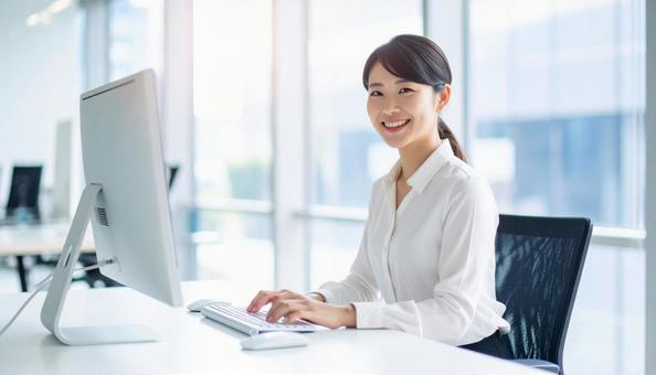 パソコンで仕事する白い服装の女性会社員 パソコンで仕事する白い服装の女性会社員の写真
