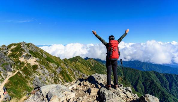 山登りで山頂で深呼吸する女性の後ろ姿 山登りで山頂で深呼吸する女性の後ろ姿の写真