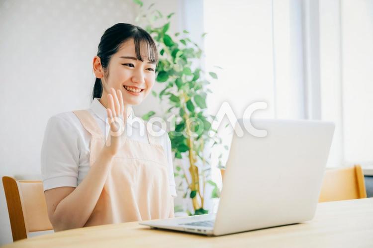 パソコンを使うエプロン姿の女性（笑顔） 介護士,ホームヘルパー,介護福祉士の写真素材