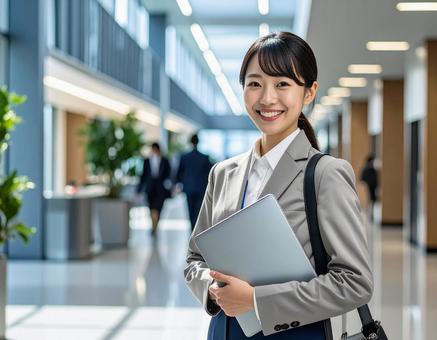 オフィスでPCを持って微笑む女性社員 オフィスでPCを持って微笑む女性社員の写真