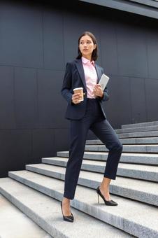 コーヒーとタブレットを持ってオフィスビルの外の階段を登っているアジア人ビジネスウーマン ビジネスウーマン,ビジネス,女性の写真素材