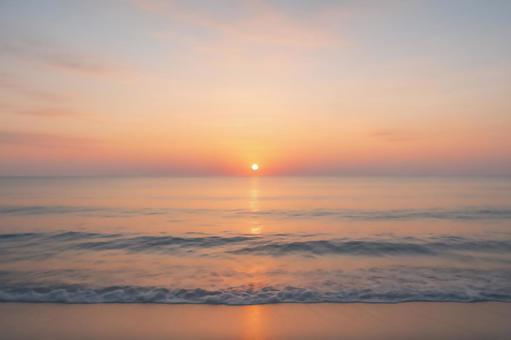 静かな海に昇る朝日の写真