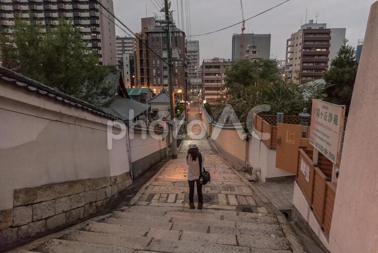 夕暮れの坂道に立つ女性 ビル,坂,坂道の写真素材
