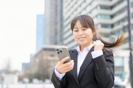 スマホを見て喜ぶ女性 スマホを見て喜ぶ女性 ビジネス,女性,ビジネスウーマンの写真素材