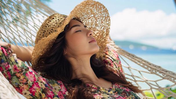 海辺のハンモックでくつろぐ女性の写真