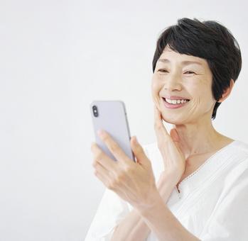 スマホ 受信 60・70代 女性 白背景 スマホ 受信 60・70代 女性 白背景の写真