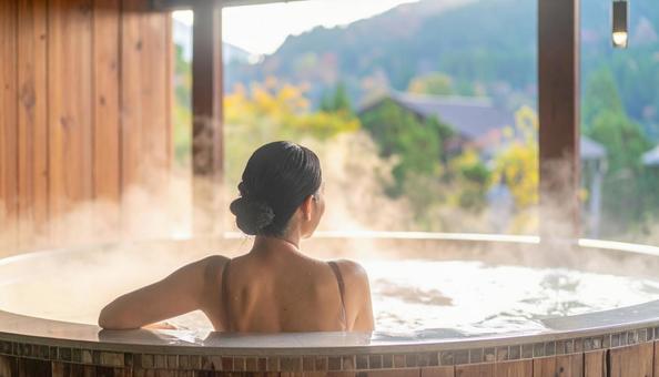 温泉につかってリラックスする若い女性の写真