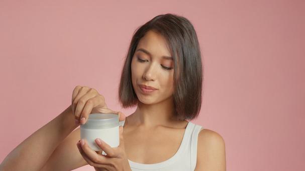 クリームジャーの蓋を開けようとしている女性 クリームジャーの蓋を開けようとしている女性の写真