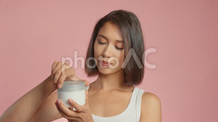 クリームジャーの蓋を開けようとしている女性 女性,外国人,アジア人の写真素材