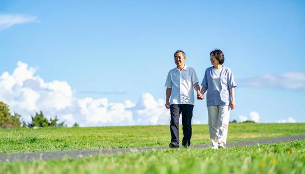 青空の下　草原を散歩するシニアの写真