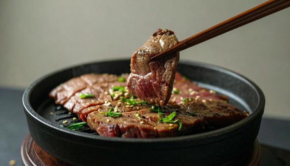 焼肉を鉄板で焼いて鉄箸ですくう 焼肉を鉄板で焼いて鉄箸ですくうの写真