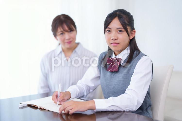 女性家庭教師と勉強しているカメラ目線の女子生徒 塾,人物,女性の写真素材