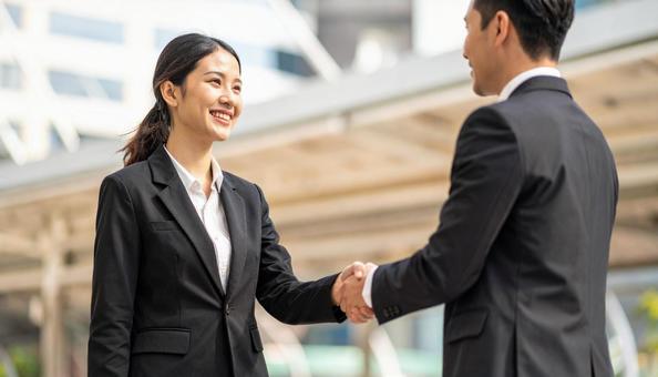 外国人ビジネスマンと握手する日本人女性 外国人ビジネスマンと握手する日本人女性の写真