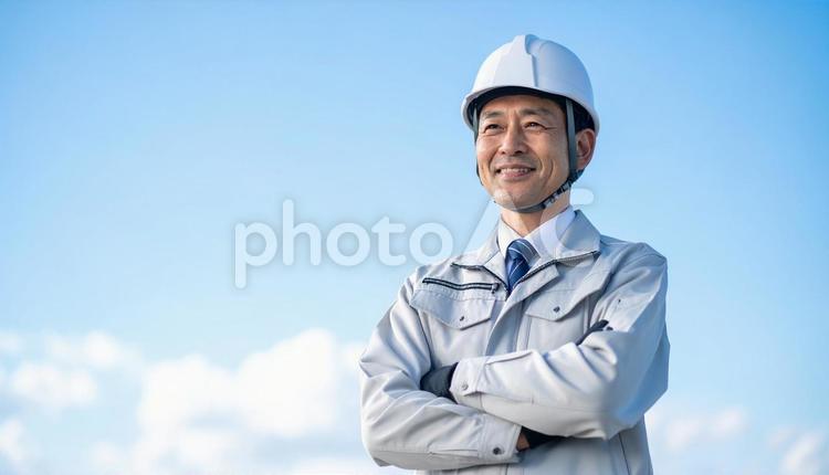 青空の下で笑顔の日本人中年男性建設作業員 作業服,男性,中年の写真素材