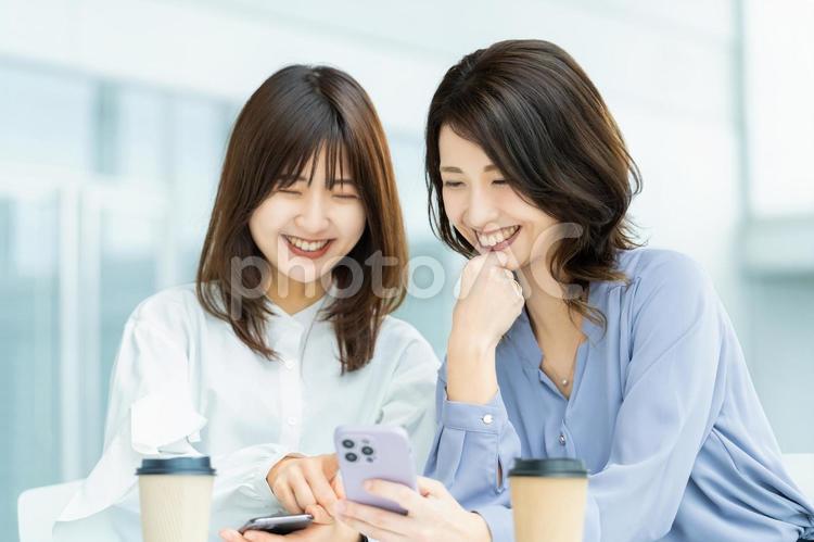 スマホを見て話す2人のビジネスウーマン 女性,ビジネス,ビジネスウーマンの写真素材