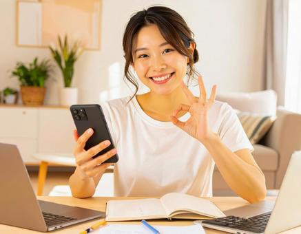 家計がうまくいきスマホ片手に微笑む女性 家計がうまくいきスマホ片手に微笑む女性の写真