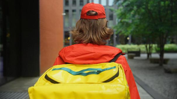 街なかを歩くフードデリバリーの男性の後ろ姿 配達,フードデリバリー,デリバリーの写真素材