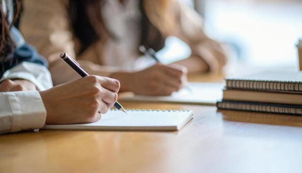 メモ帳を用いて筆談をする若い女性の友人の写真