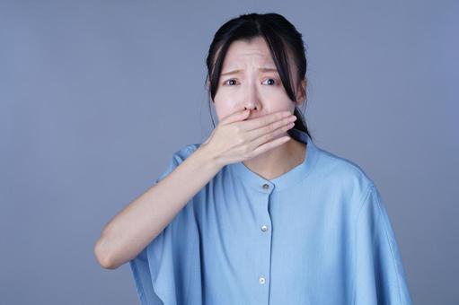 口を手で覆って驚いた青い服の女性 女性,口を覆う,吐き気の写真素材
