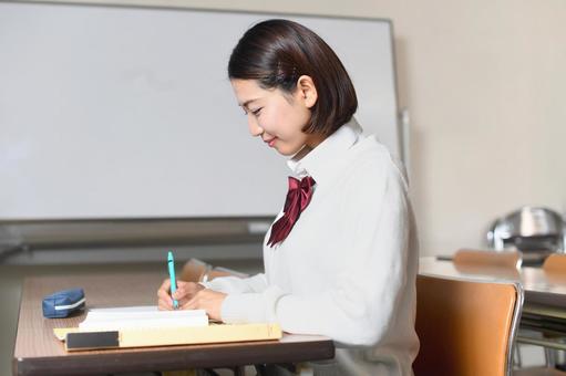 教室で勉強をする笑顔の女子学生の横顔 教室で勉強をする笑顔の女子学生の横顔の写真