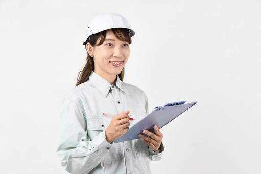 ボードを持つ作業服姿の若いアジア人女性 ボードを持つ作業服姿の若いアジア人女性 現場作業,作業着,安全管理の写真素材