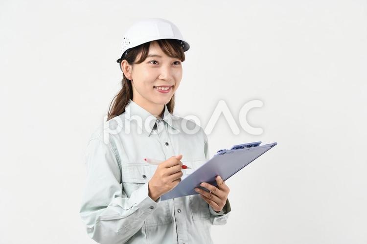 ボードを持つ作業服姿の若いアジア人女性 現場作業,作業着,安全管理の写真素材