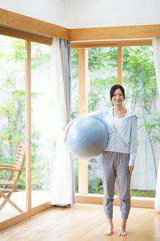 バランスボールを持ち立つ女性 女性,日本人,バランスボールの写真素材