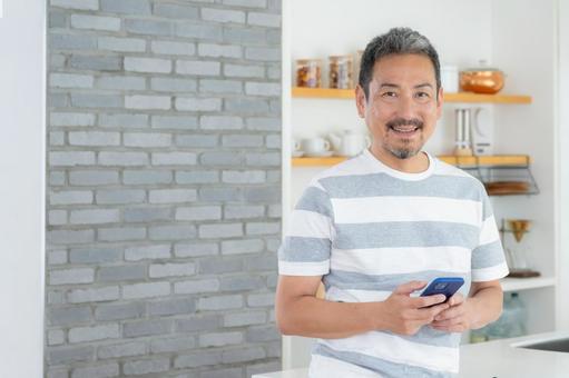 キッチンでスマホを使うミドルの男性 キッチンでスマホを使うミドルの男性 男性,スマホ,ミドルの写真素材