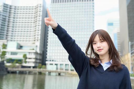 ビル街で大きく指をさす女子高生 ビル街で大きく指をさす女子高生 高校生,女子高生,指さしの写真素材